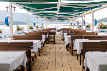 Outdoor cafe or restaurant with sea view and empty chairs. Coastal relaxation, summer tourism, and beachfront dining in the Mediterranean region.