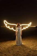 Long exposure photograph of an attractive Caucasian woman in a wedding dress posing on the beach at...