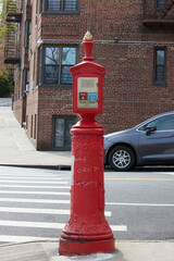 an antique victorian era fire alarm call box on a corner of a new york city street in manhattan, for calling police and fire department in case of emergency