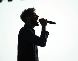 Silhouette of young male singer performing on stage. Musician holds microphone singing with passion. Vocalist entertains audience in concert. Entertainment, live music performance.