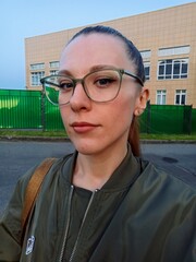 Portrait of a beautiful young woman in glasses on the street.