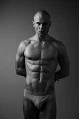 Fototapeta premium Muscular man posing confidently in black and white, showcasing strength and determination. The image emphasizes the male physique and powerful presence.