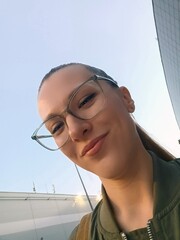 Portrait of a beautiful young woman with glasses on the background of the city