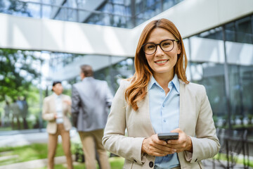 Smart businesswoman use cellphone in front of modern office building