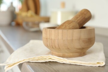 Mortar and pestle on wooden table in kitchen, closeup