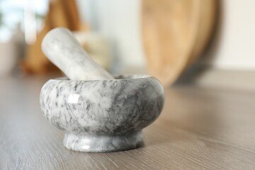 Marble mortar and pestle on wooden table in kitchen, closeup. Space for text