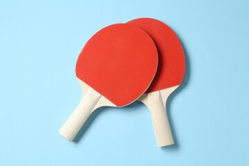 Ping pong rackets on light blue background, flat lay