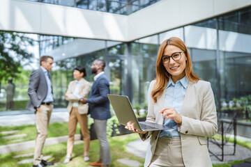Smart businesswoman use laptop in front of modern office building