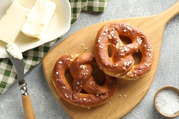 Tasty pretzels with salt and butter on light grey table, flat lay