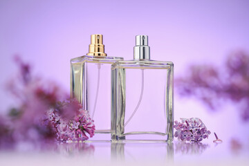 Bottles of perfume and lilac flowers on mirror surface against violet gradient background,...