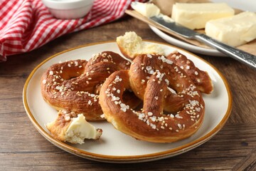 Tasty pretzels with salt and butter on wooden table, closeup