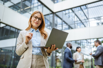Smart businesswoman use laptop in front of modern office building