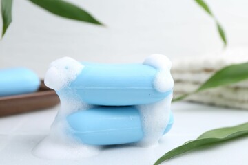 Soap bars with foam on white table, closeup