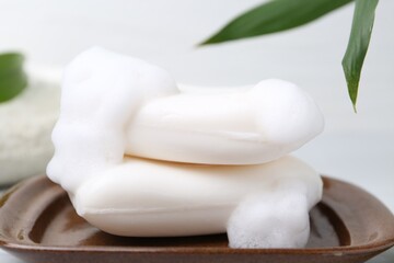Soap bars with foam on white table, closeup