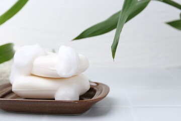 Soap bars with foam on white table, closeup. Space for text