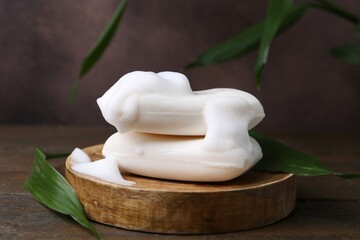 Soap bars with foam on wooden table, closeup