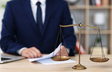 Judge working and scales on desk indoors, selective focus