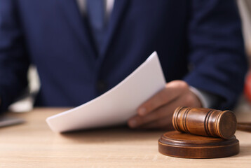 Judge working and gavel on desk indoors, selective focus