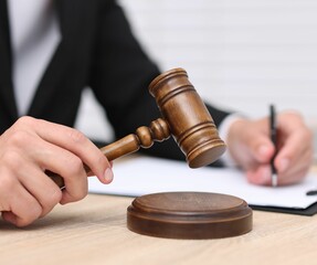 Judge with gavel working at desk indoors, closeup