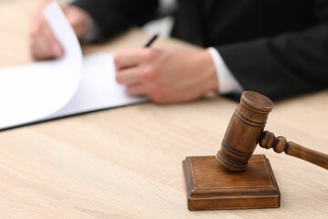 Judge working and gavel on desk indoors, selective focus