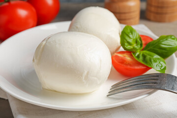 Tasty mozzarella cheese balls, tomatoes and basil on table, closeup