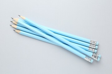 Many graphite pencils with erasers on light grey background, flat lay