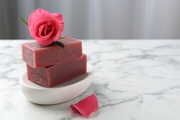 Soap bars and beautiful rose on white marble table, closeup. Space for text