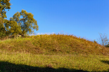 Fototapeta premium Hill covered with green grass against blue sky