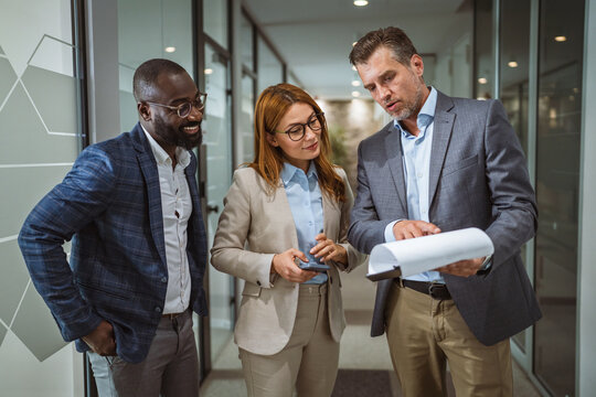 three businesspeople colleagues discuss and check documents together