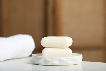 Soap bars and towel on white table indoors, closeup