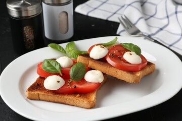 Tasty sandwiches with mozzarella cheese, tomatoes and basil on dark table, closeup