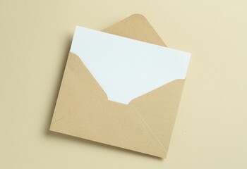 Blank invitation card and envelope on beige background, top view