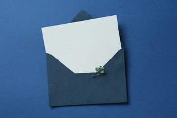 Blank invitation card and envelope on blue background, top view. Space for design