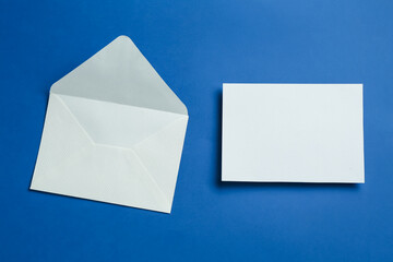 Blank invitation card and envelope on blue background, flat lay. Space for design