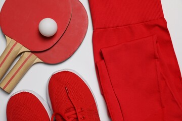 Sportswear, sneakers, ping pong rackets and ball on white background, flat lay