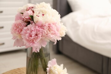 Beautiful peonies in vase on wooden table indoors, closeup. Space for text
