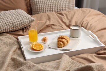 Tray with delicious breakfast on bed indoors, closeup