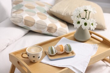 Tray with delicious breakfast and flowers on bed indoors, closeup. Space for text