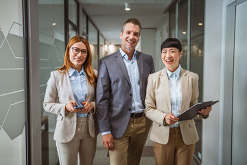 Portrait of multicultural colleagues stand and pose at company hallway