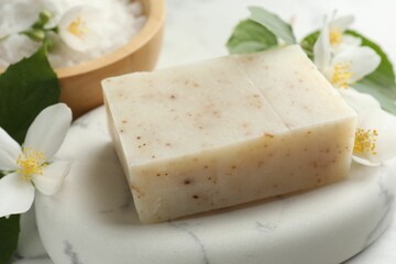 Soap bar, sea salt and jasmine flowers on table, closeup