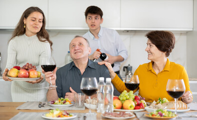 Father and mother together with adult children talking at the dinner table at home