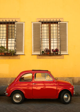 Small red car against yellow wall, Florence, Italy, Europe