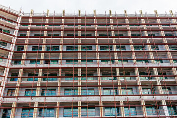 Modern glass building under construction with full scaffolding. Urban development, contemporary...