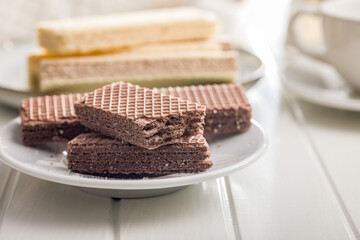 Sweet wafers filled with chocolate cream on plate on white table.