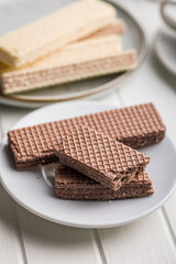 Sweet wafers filled with chocolate cream on plate on white table.