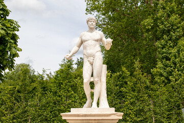 Obraz premium Nude Male Statue Holding Fruit in Garden Setting at Palace of Versailles, Paris.