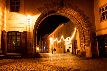Hermosa escena de las calles de český krumlov de noche, con una par de siluetas caminado a lo lejos