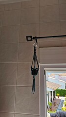 Black Macrame Plant Hanger Suspended on Curtain Rod Indoors
