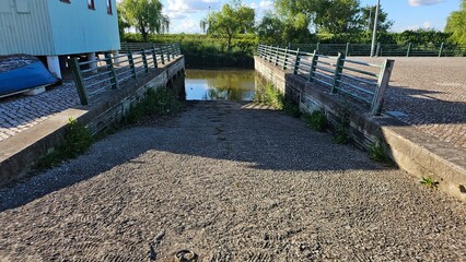 Boat ramp with metal guardrails leading into a calm canal