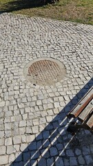 Round Manhole Cover Embedded in Cobblestone Pavement